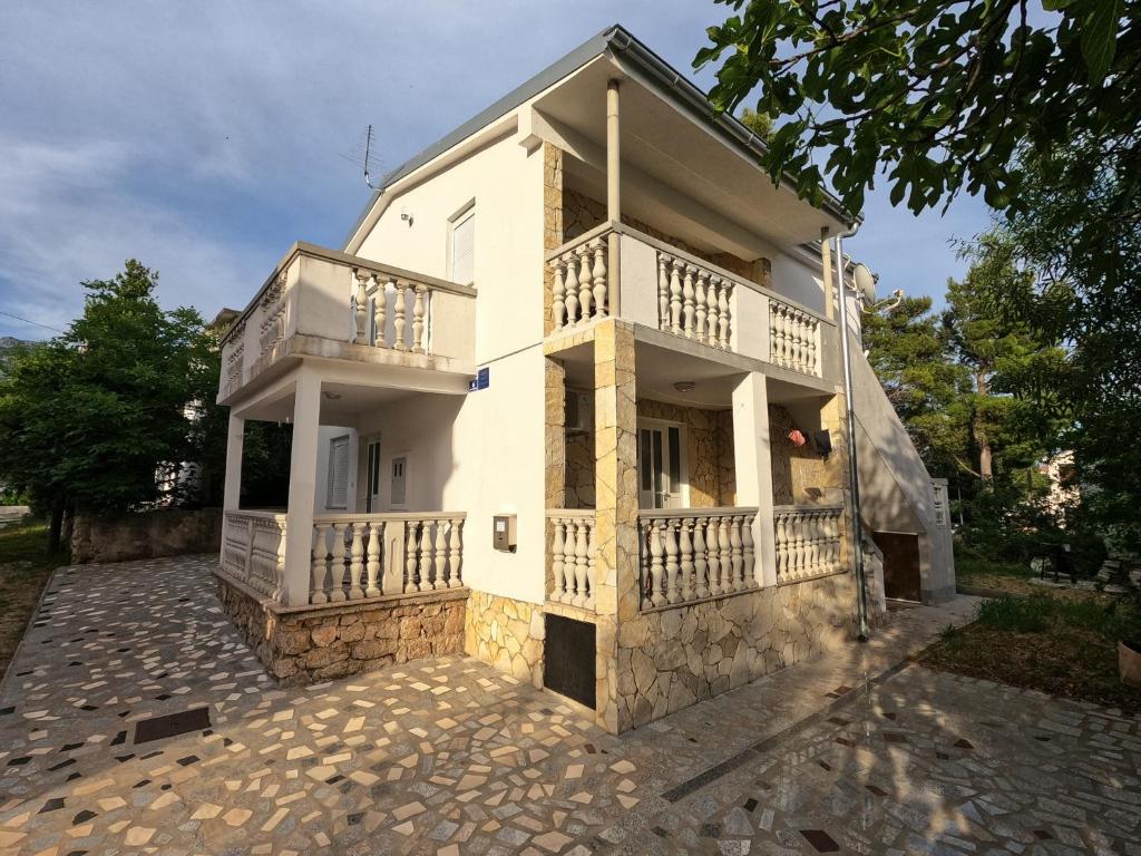 a white house with a balcony on a driveway at Apartments Lana - 30 m from the sea in Seline
