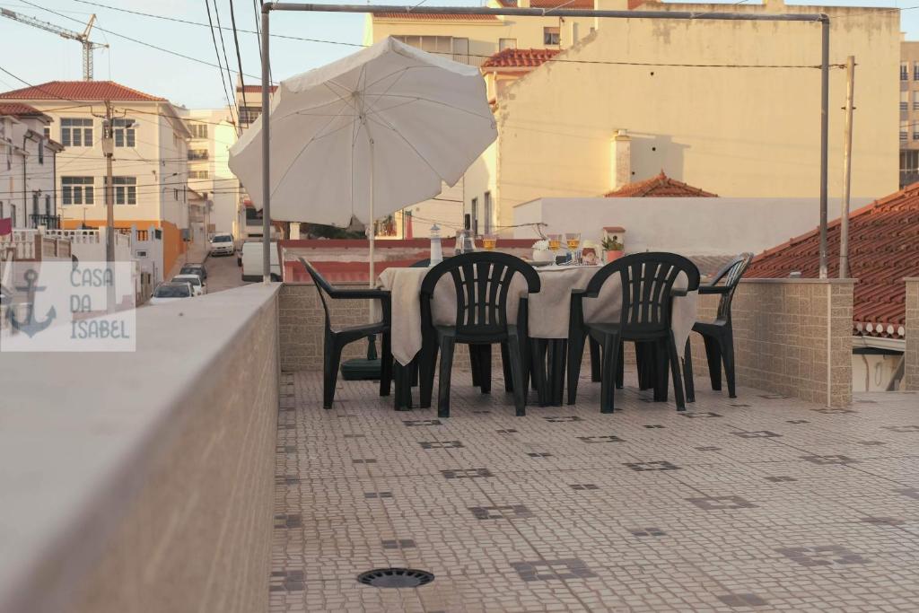 einen Tisch mit vier Stühlen und einem Sonnenschirm auf dem Balkon in der Unterkunft Casa da Isabel - Centro da Nazaré in Nazaré