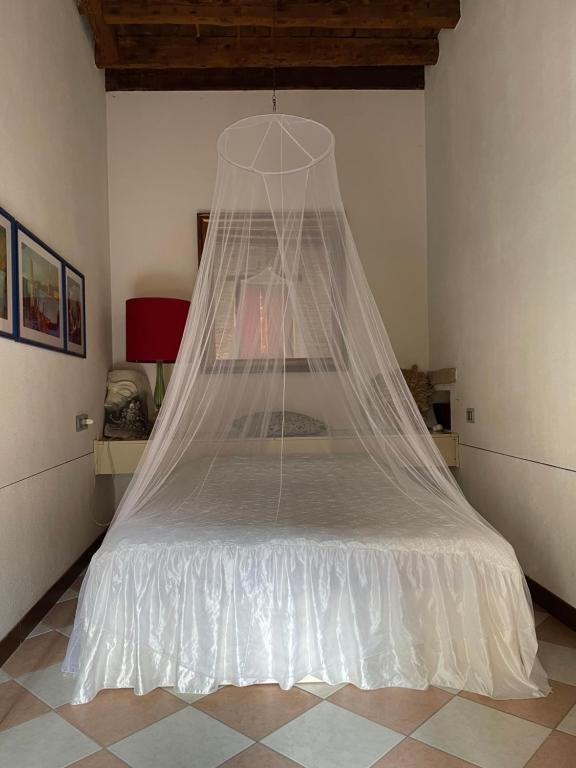 a bed with a net on it in a room at In a lovely garden Biennale Flat in Venice