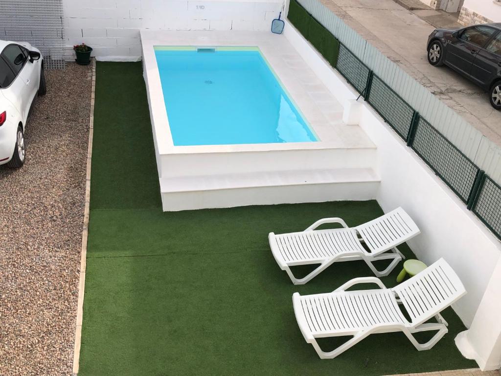 two lawn chairs and a swimming pool on a house at LCC rooms in Couço