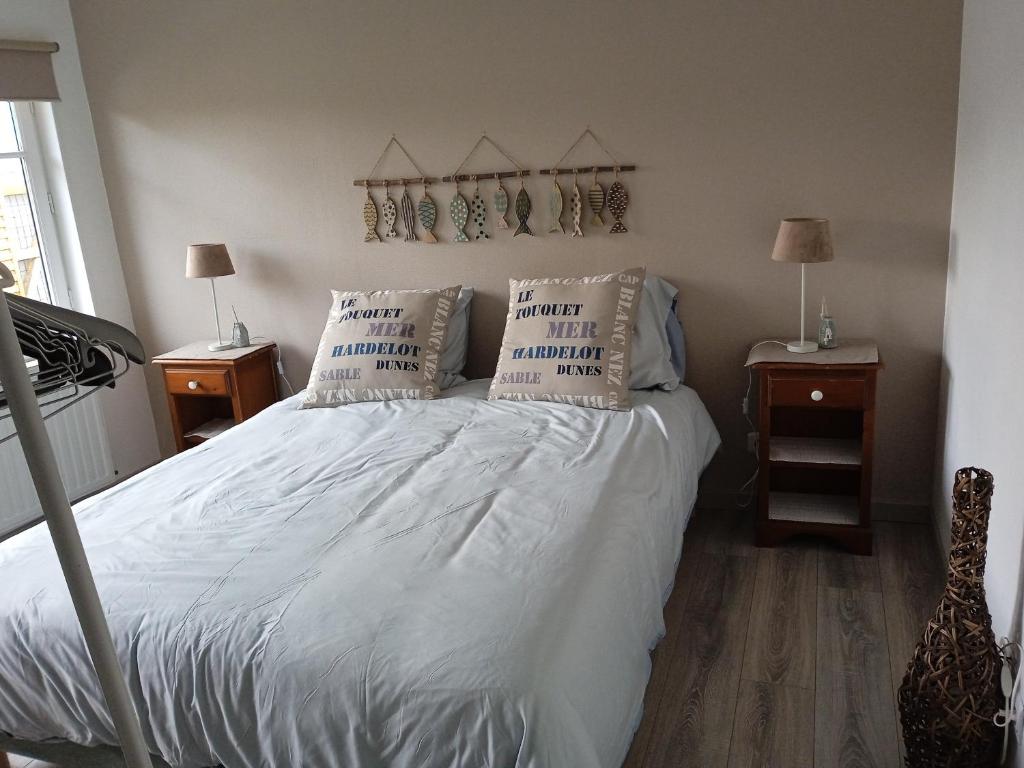 um quarto com uma cama com lençóis brancos e almofadas em HOTE MERLIMONT em Merlimont