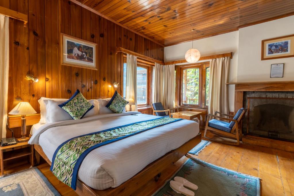 a bedroom with a large bed and a fireplace at Hotel Negi's Mayflower A heritage Since 1965 in Manāli