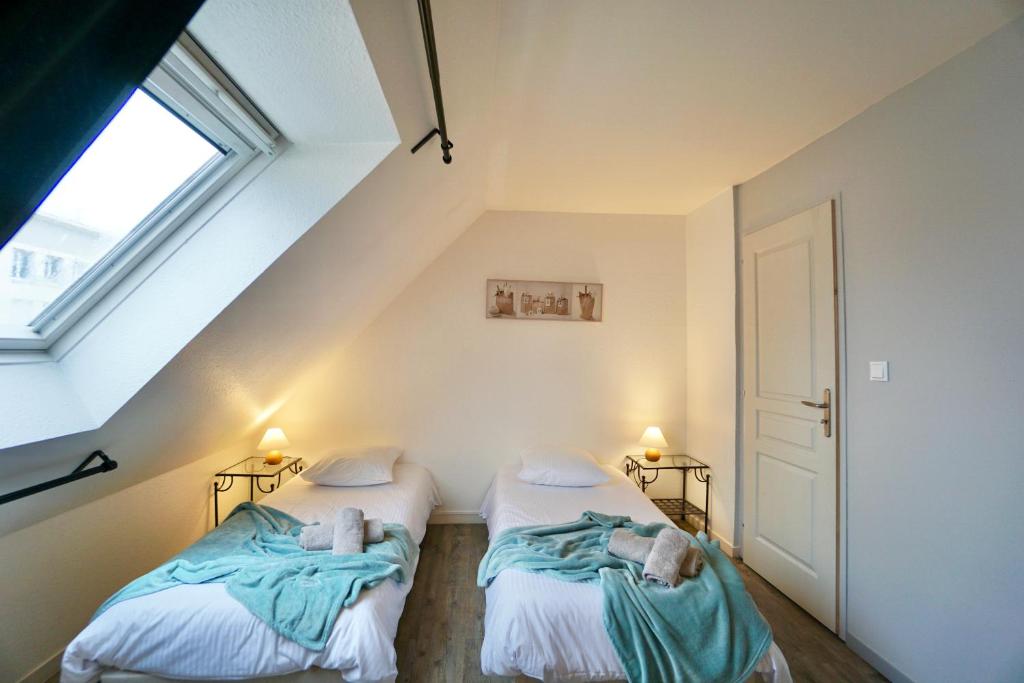 two beds in a attic room with a window at Le duplex du quai mer in Concarneau