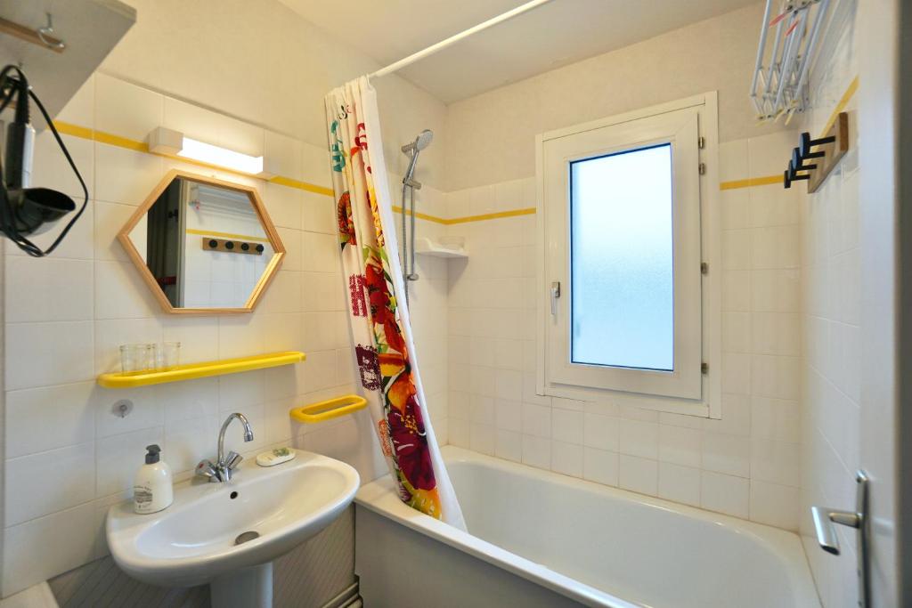 a bathroom with a sink and a tub and a mirror at Le duplex du quai mer in Concarneau