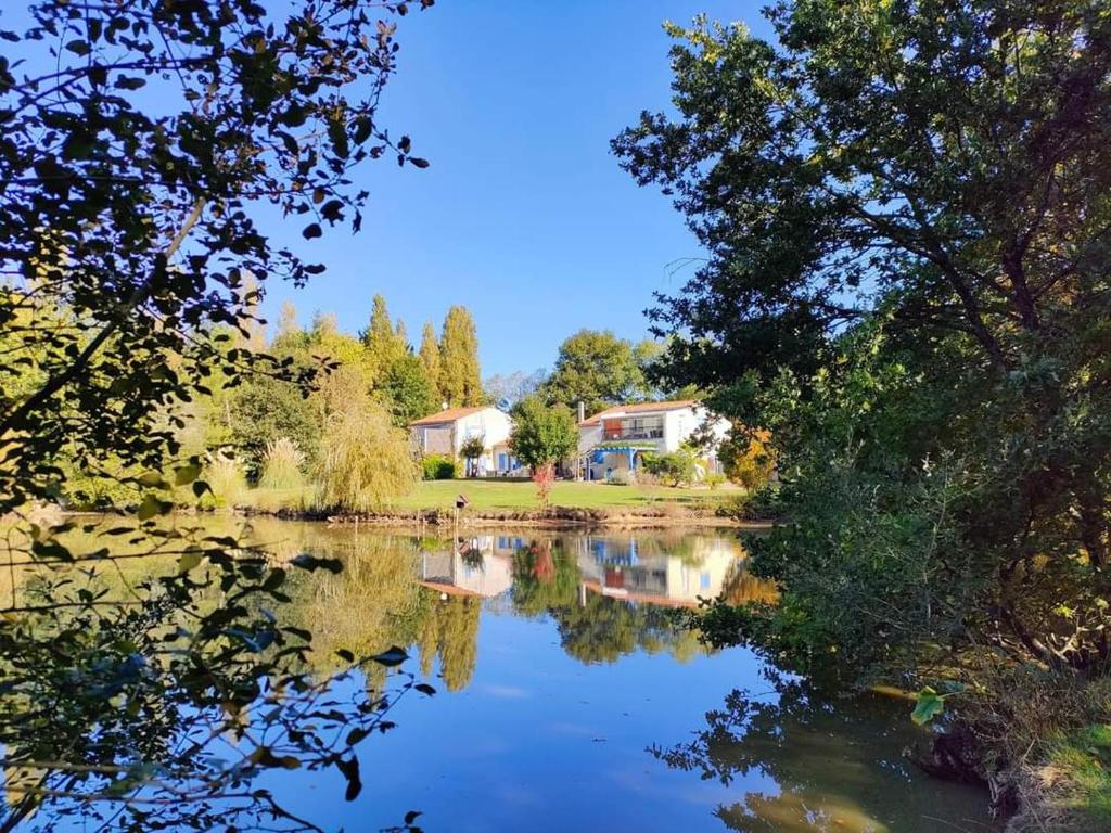 Gîte Douceur de vivre في Saint-Avaugourd-des-Landes: اطلاله على بحيره فيها اشجار وبيوت