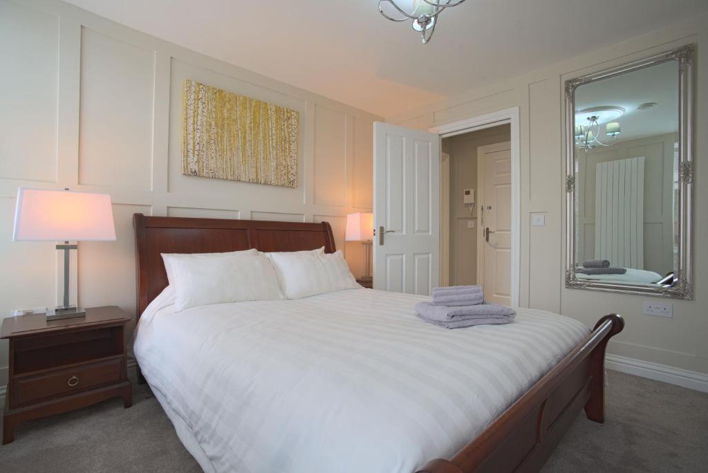 1 dormitorio con 1 cama blanca grande y espejo en Harper Luxe Serviced Apartments Dunstable, en Dunstable