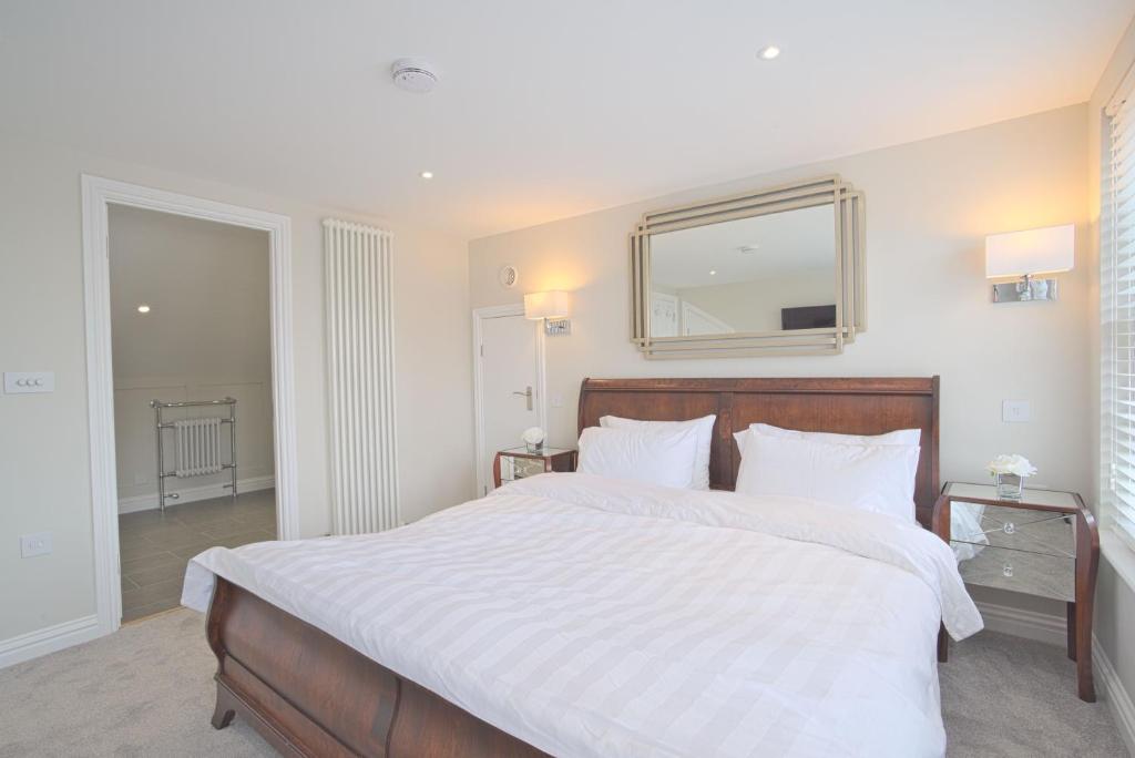 Harper Luxe Serviced Apartments Dunstable في دانستابل: غرفة نوم بسرير ابيض كبير ومرآة