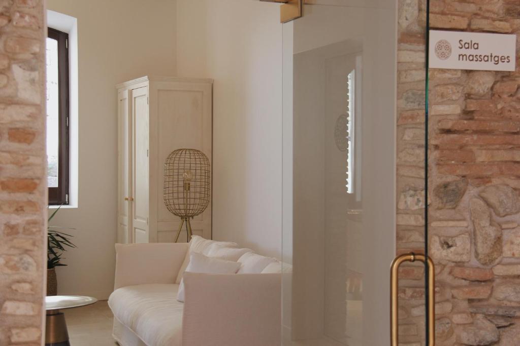 a living room with a white couch and a brick wall at Hotel Palau Macelli in Castelló d'Empúries