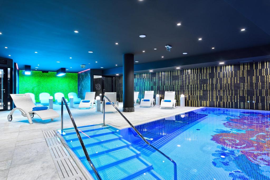 a swimming pool in a hotel with white chairs at Hotel Ferreus Modern Art Deco in Kraków