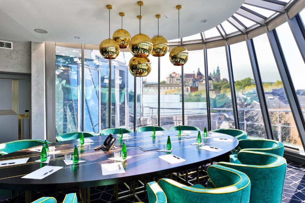 a conference room with a table and green chairs at Hotel Ferreus Modern Art Deco in Krakow