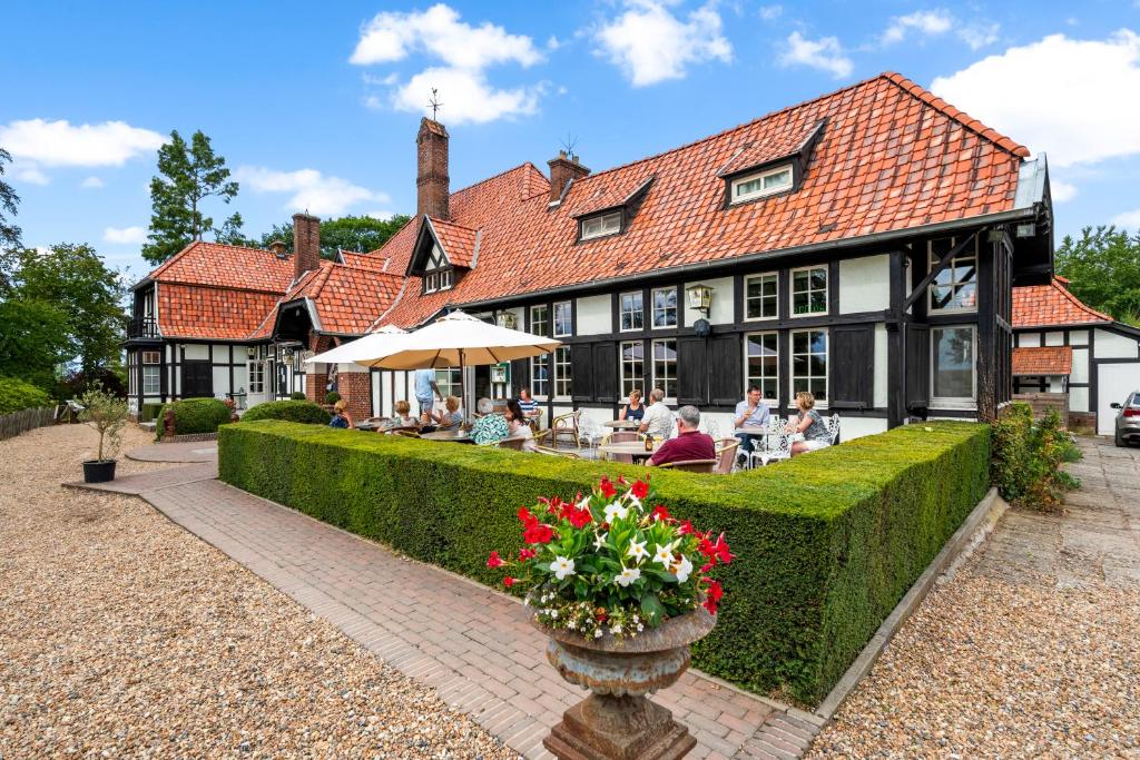 um edifício com pessoas sentadas em mesas à frente dele em Hotel Kasteelhof 'T Hooghe em Ypres