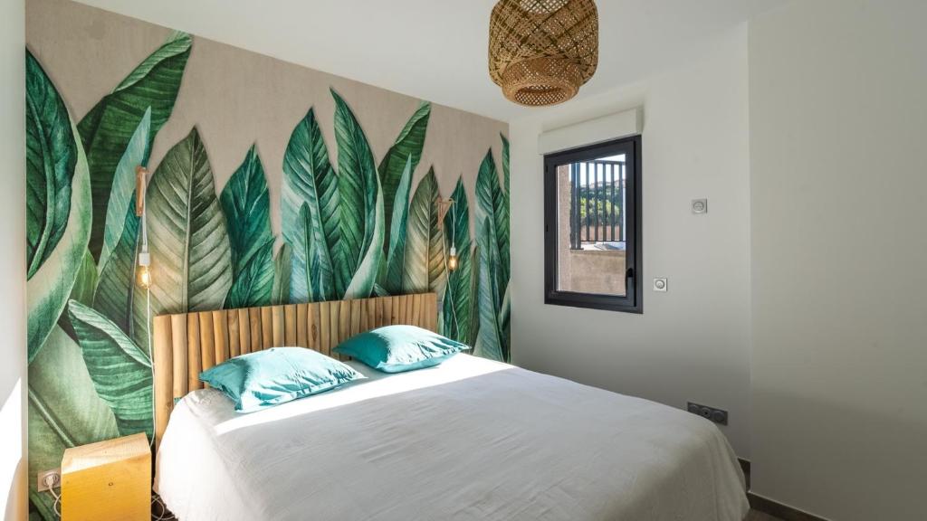 a bedroom with a bed with a mural of leaves at Les Rivages de Stagnola Appartement T3 vue mer et montagne plage 200m climatisé in Pietrosella