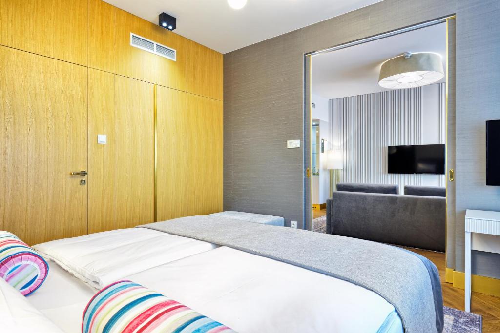 a bedroom with a bed and a couch and a television at Hotel Ferreus Modern Art Deco in Krakow