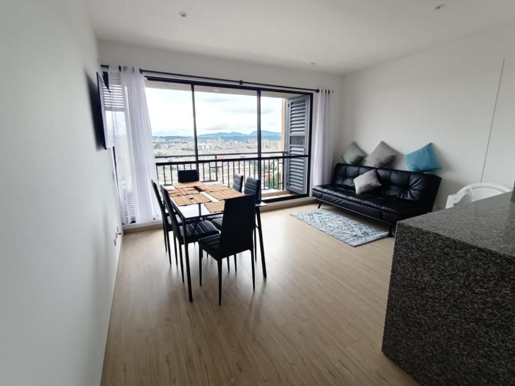 a living room with a table and chairs and a large window at Apartamento en zona norte bogota in Bogotá