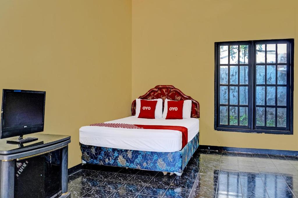 Dormitorio con cama, escritorio y TV en SPOT ON 91798 Hotel Grand Mutiara en Cikampek