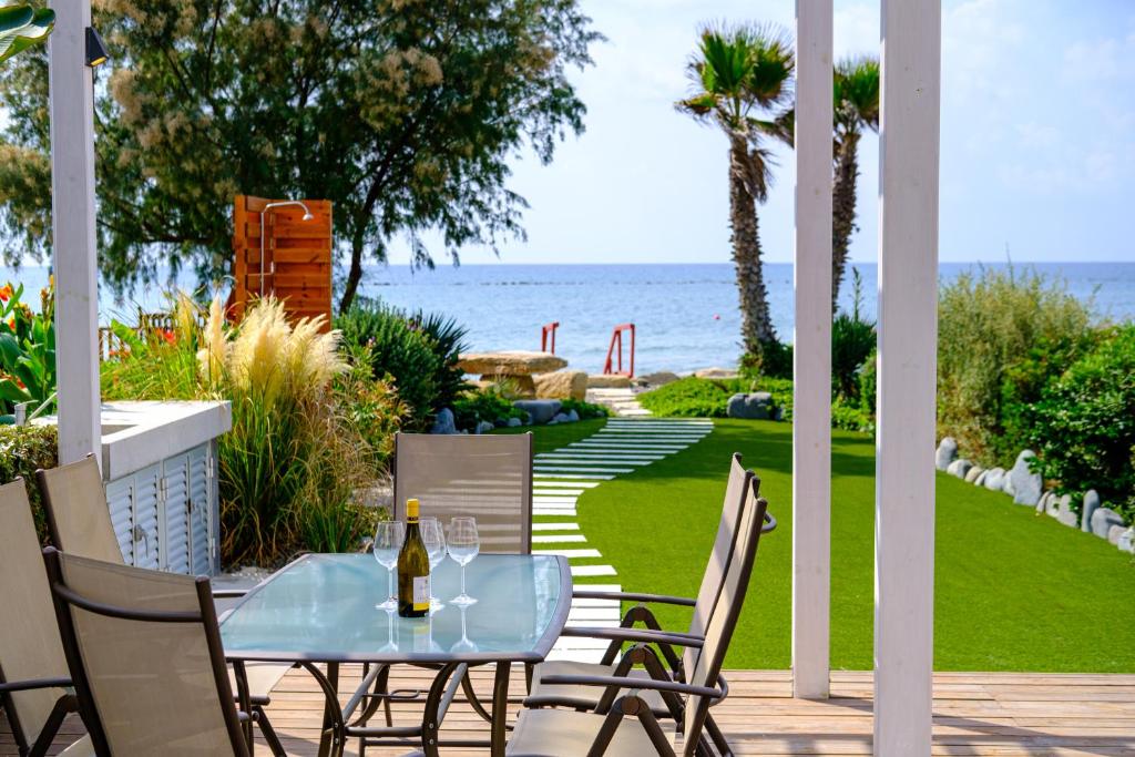 a table and chairs on a patio with a view of the ocean at The MedView Garden House in Pervolia