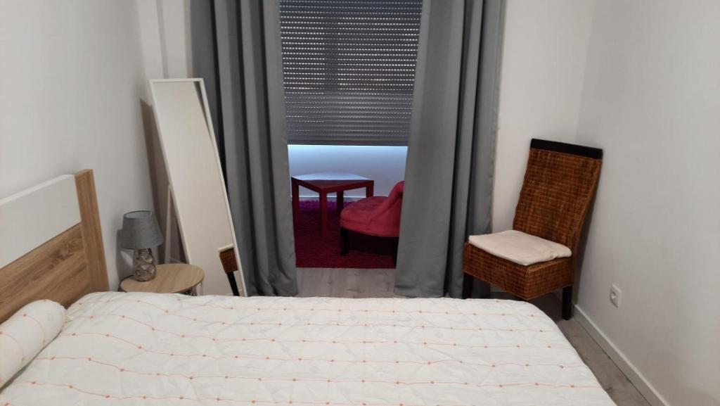 a bedroom with a bed and a chair and a window at Apartamento da Antónia in Viseu
