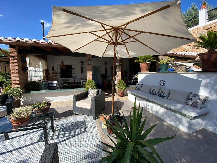 a patio with a couch and an umbrella at Fantastic Private Villa with pool near Ardales and Caminito del Rey in Ardales