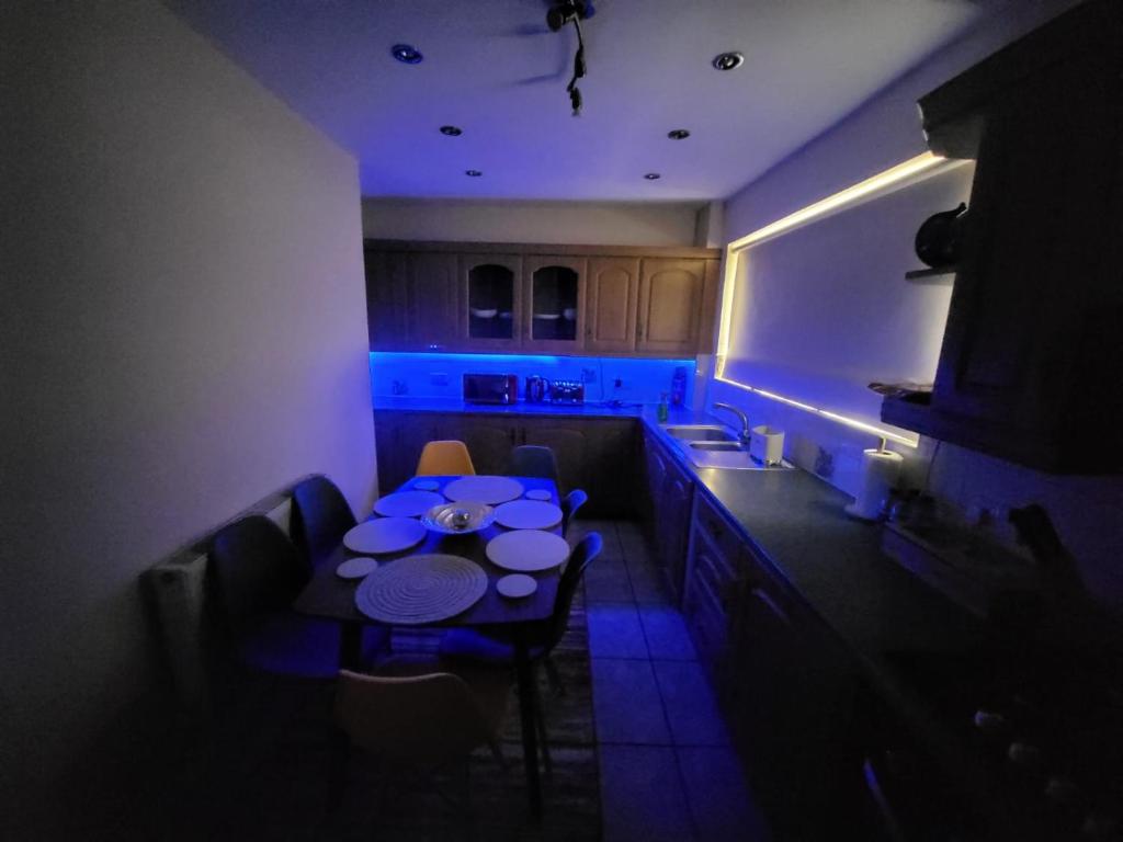 a kitchen with a table and blue lighting in a room at Spacious serviced home with free parking & Wi-Fi in Willenhall
