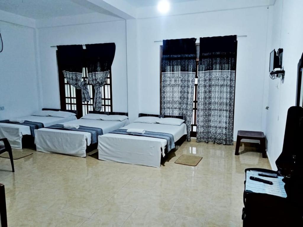 una camera con quattro letti e finestre di Fair View Bungalow a Kataragama