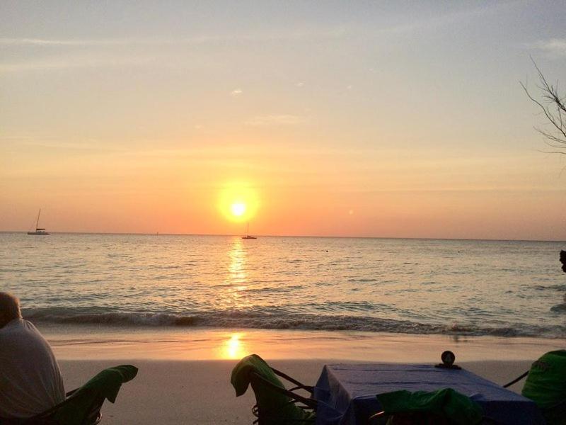 two people sitting on the beach watching the sunset at Ondo House in Nungwi