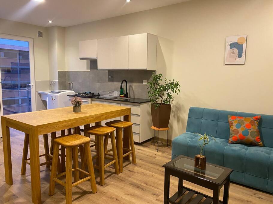 cocina y sala de estar con mesa y sofá azul en Americas Apartment en Sucre