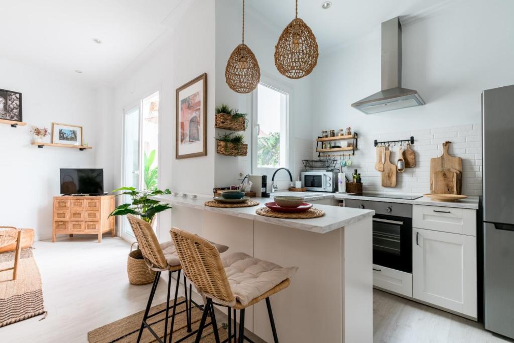 kuchnia z białymi urządzeniami i blatem ze stołkami w obiekcie Oasis con patio y encanto en centro Sevilla w Sewilli