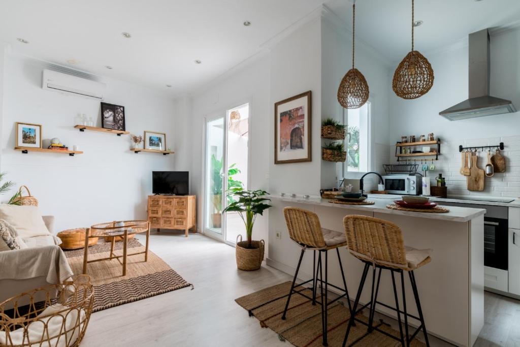 uma cozinha e sala de estar com um balcão e cadeiras em Oasis con patio y encanto en centro Sevilla em Sevilha