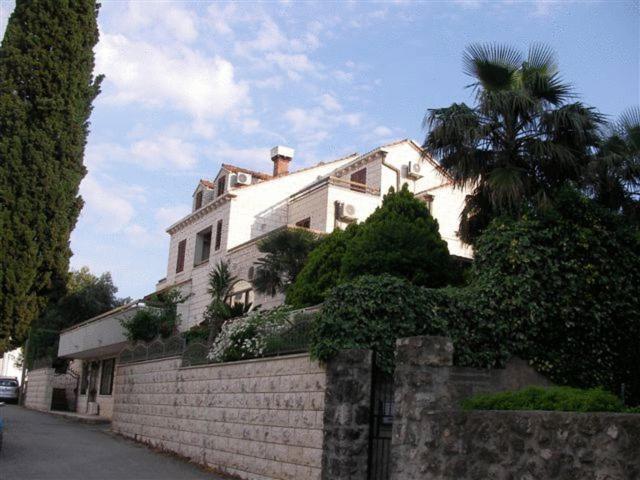 una grande casa bianca su un muro con una palma di Villa Franovic a Dubrovnik