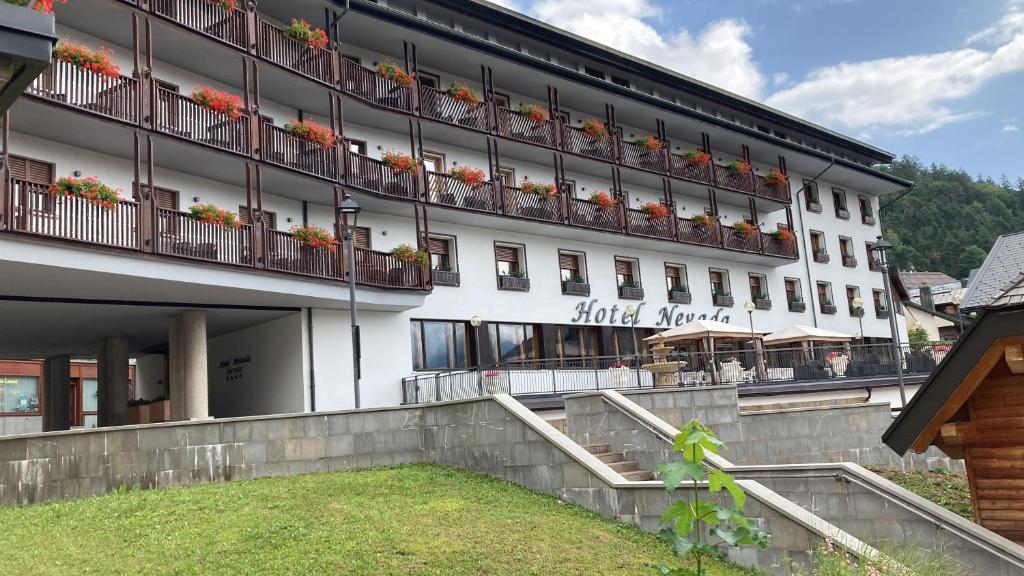 ein großes weißes Gebäude mit Blumen auf den Balkonen in der Unterkunft Hotel Nevada in Tarvis