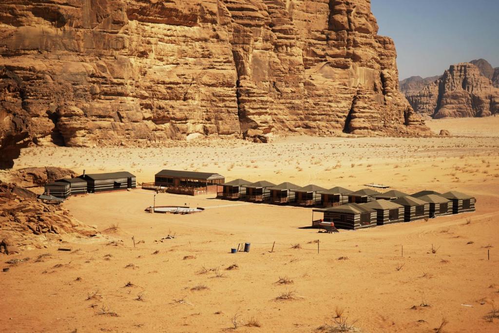 a group of shelters in the desert near a cliff at Salman Zwaidh Camp in Wadi Rum