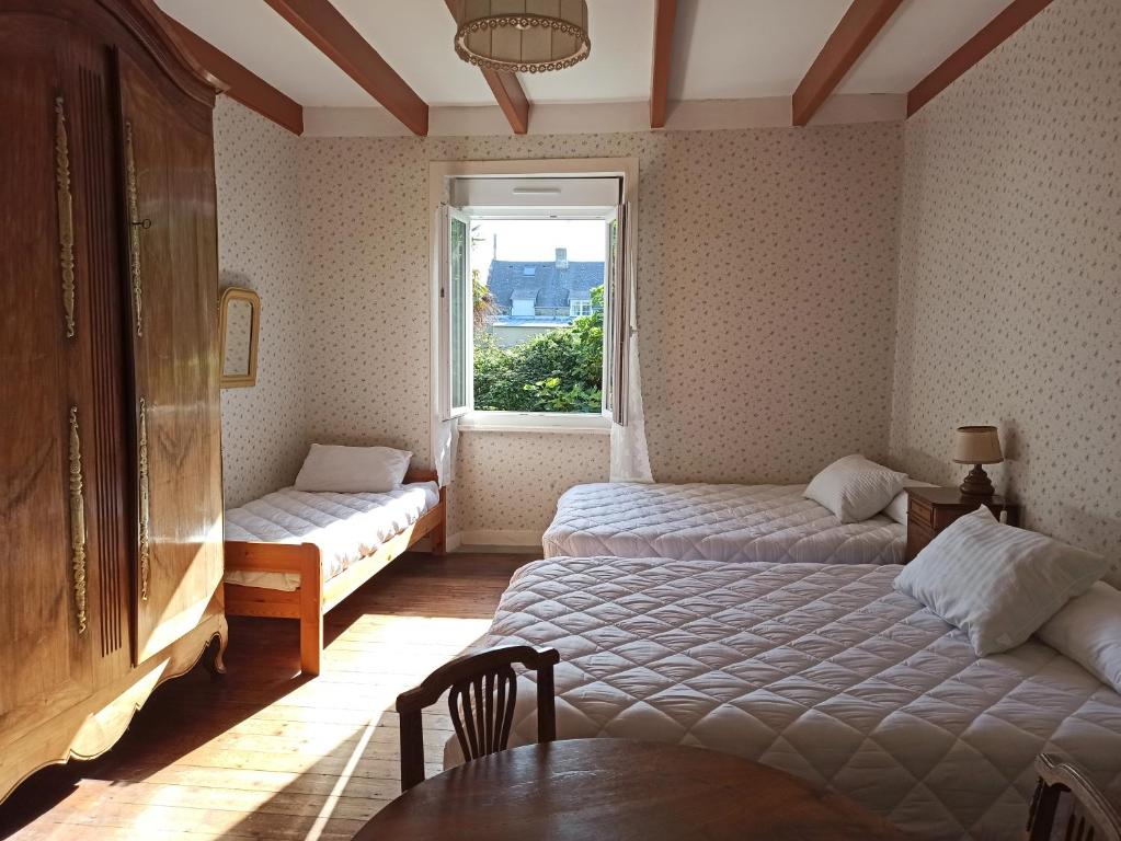 una camera con due letti, una finestra e un tavolo di Maison Cancale Port-Mer a Cancale