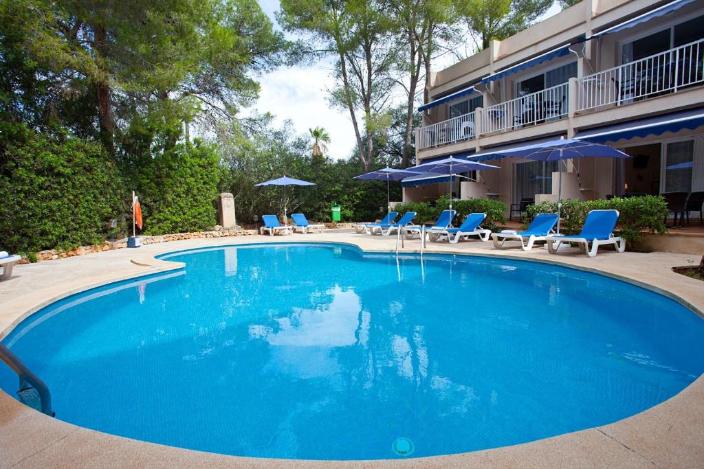 a large blue swimming pool with chairs and umbrellas at Apartamentos Cala Murada Minigolf in Cala Murada
