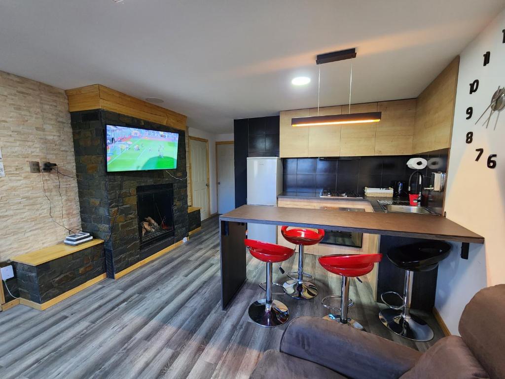 eine Küche mit einer Bar mit roten Hockern und einem Kamin in der Unterkunft Nui 2 apartamento in Punta Arenas