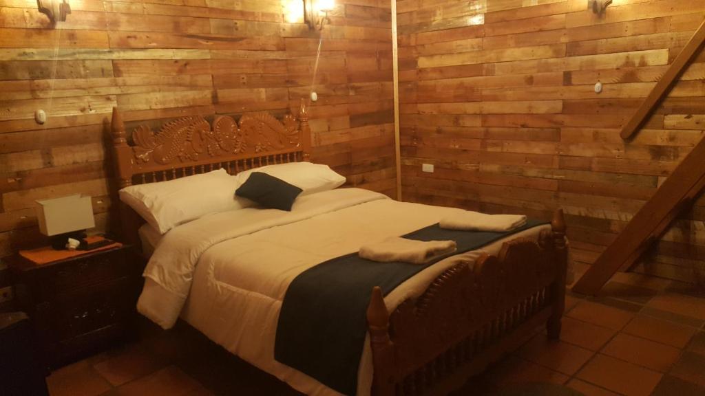 1 dormitorio con 1 cama con pared de madera en Hotel Chalet Casa Grande, en Nobsa