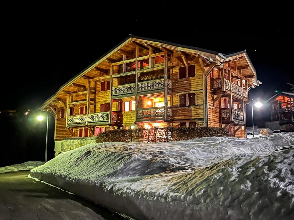 a log cabin in the snow at night at Chalet l'Arnica in Les Gets