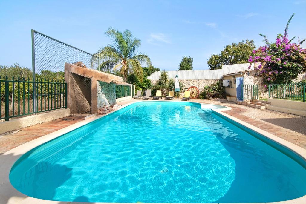 a swimming pool with blue water in a yard at Casa Rústica in Silves