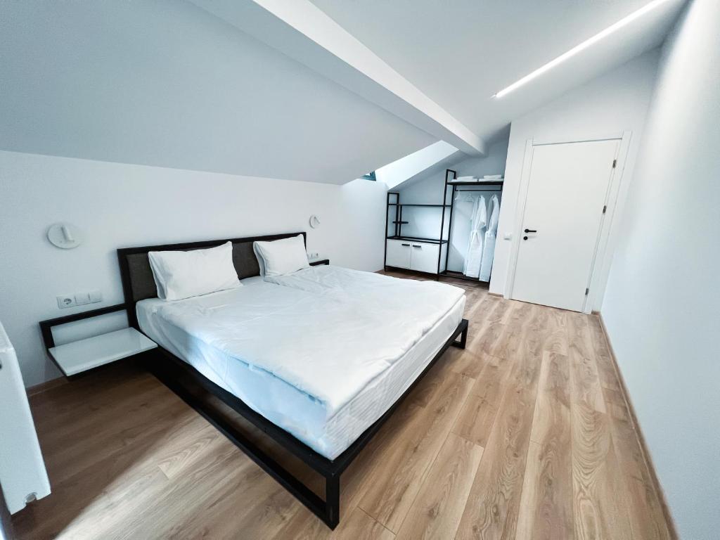 um quarto com uma cama branca e piso em madeira em Kazbegi Apartments em Stepantsminda