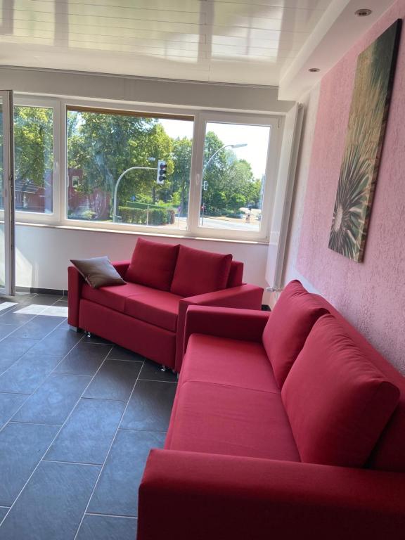 una sala de estar con 2 sofás rojos y ventanas en MarlFlats, en Marl