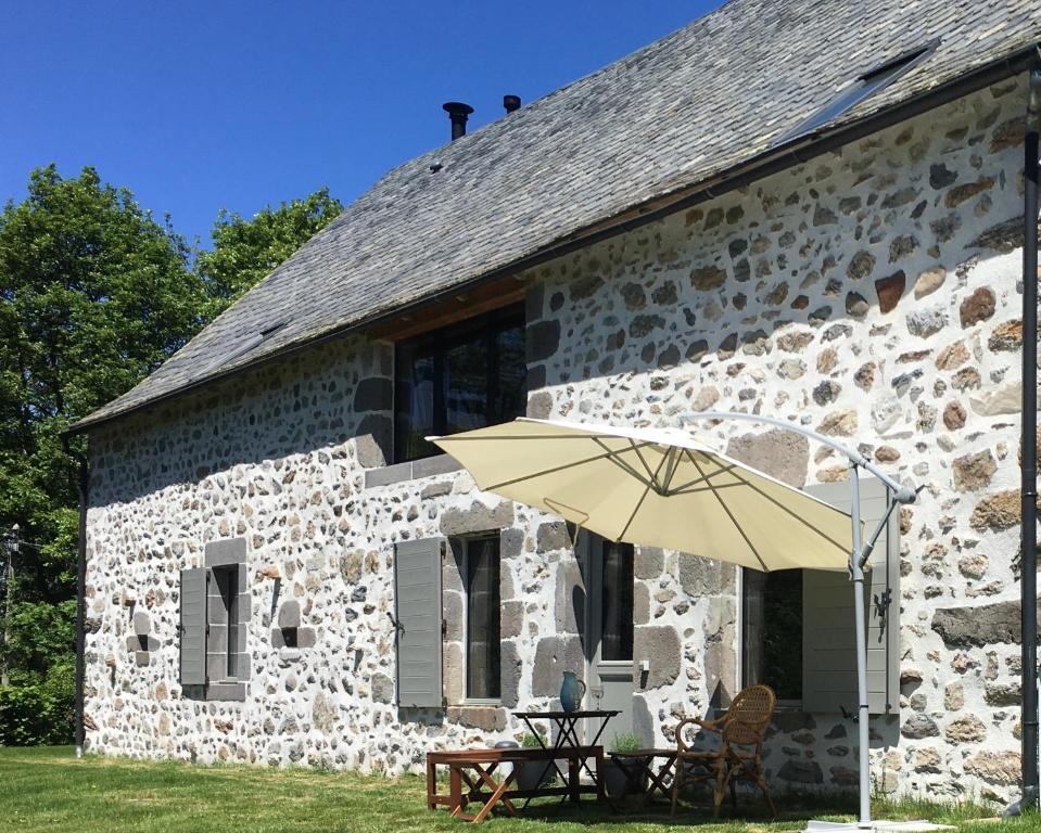 a stone building with a table and an umbrella at La Grange De L’Abille in Marchastel
