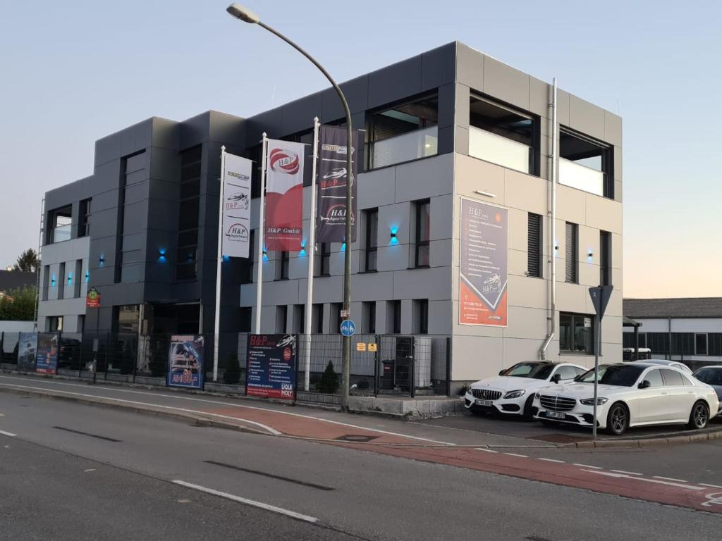 due auto bianche parcheggiate di fronte a un edificio di HP Apartments a Neu-Ulm