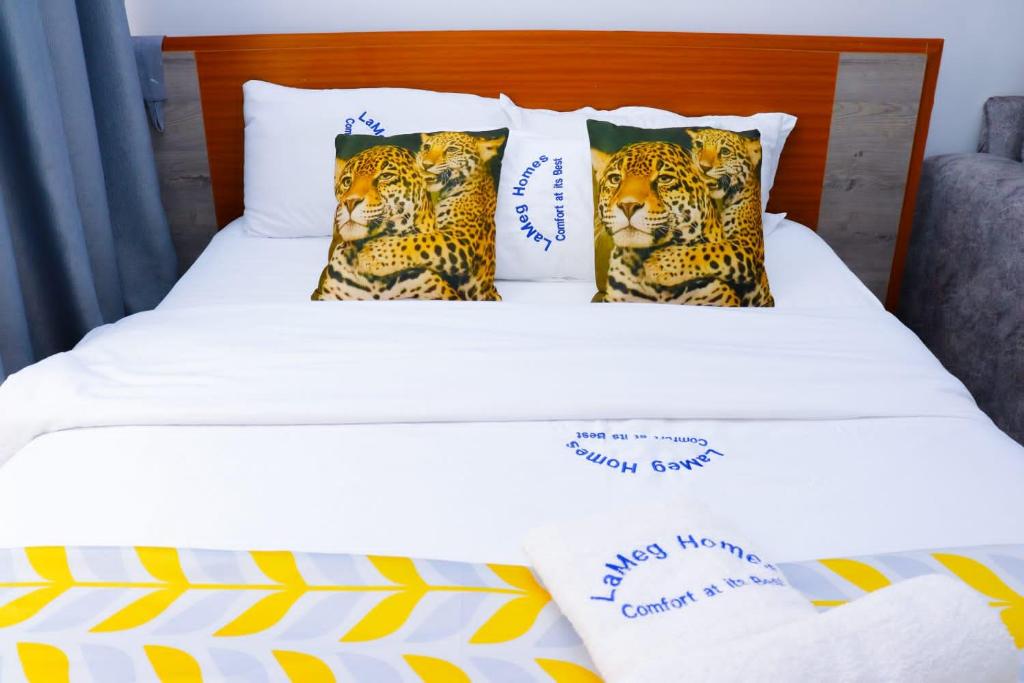 ein weißes Bett mit zwei Leopardenkissen darauf in der Unterkunft LaMeg Furnished Studio in Coral Bells Apartment in Kiambu