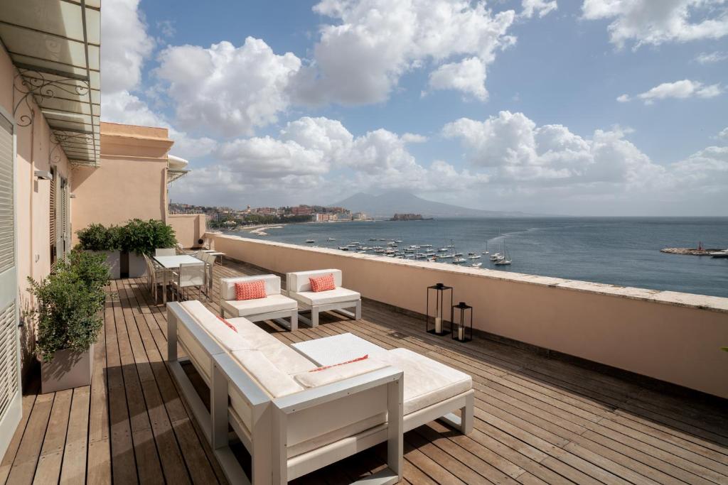 a balcony with chairs and a view of the ocean at Caracciolo 13 Rooftop & Suites in Naples