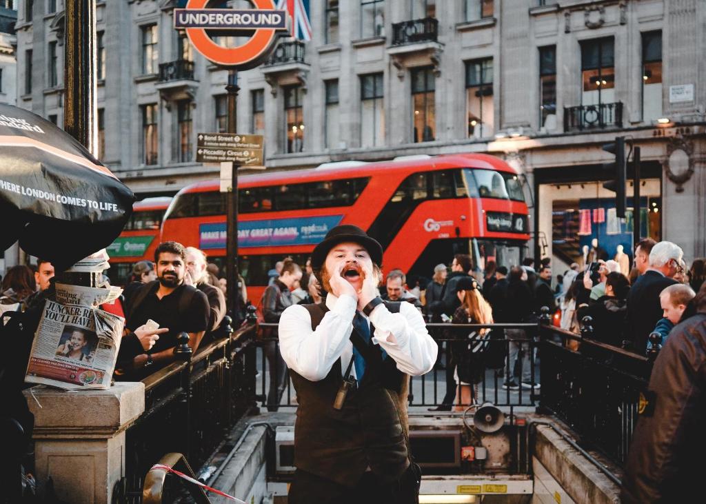 Une personne debout dans une rue urbaine animée parlant sur un téléphone portable dans l'établissement Stay at Piccadilly, à Londres