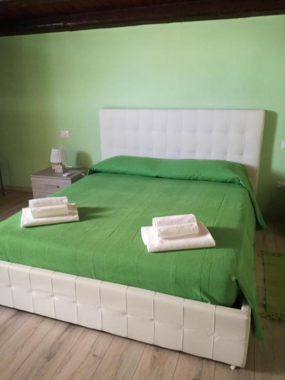 a large white bed with green sheets and towels on it at Il soppalco in Avola