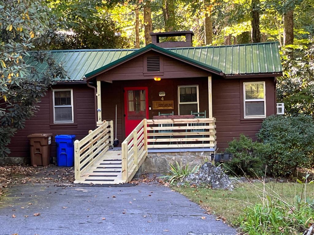 una pequeña casa con puerta roja y porche en Cozy Cabin Pet Friendly ADA Compatible en Maggie Valley