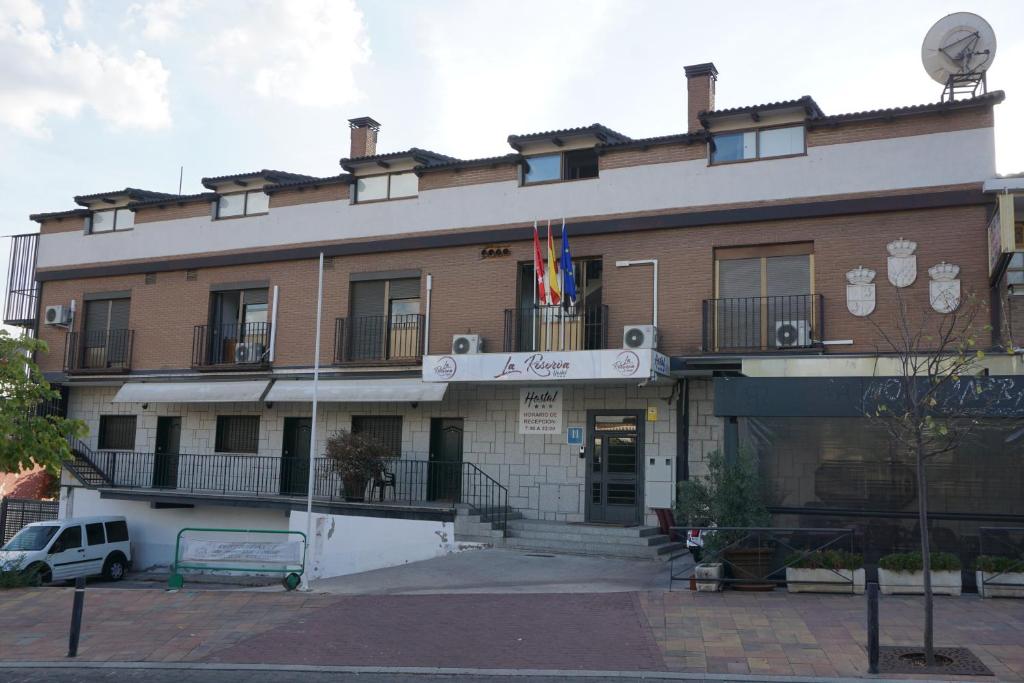 un edificio con una bandera en la parte delantera en Hostal La Reserva, en Cobeña