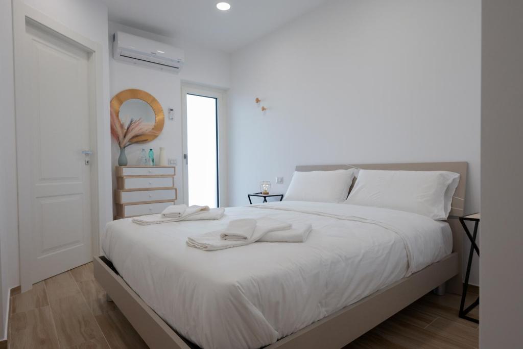 1 dormitorio blanco con 1 cama grande con sábanas blancas en All'Uscita B&b, en Éboli