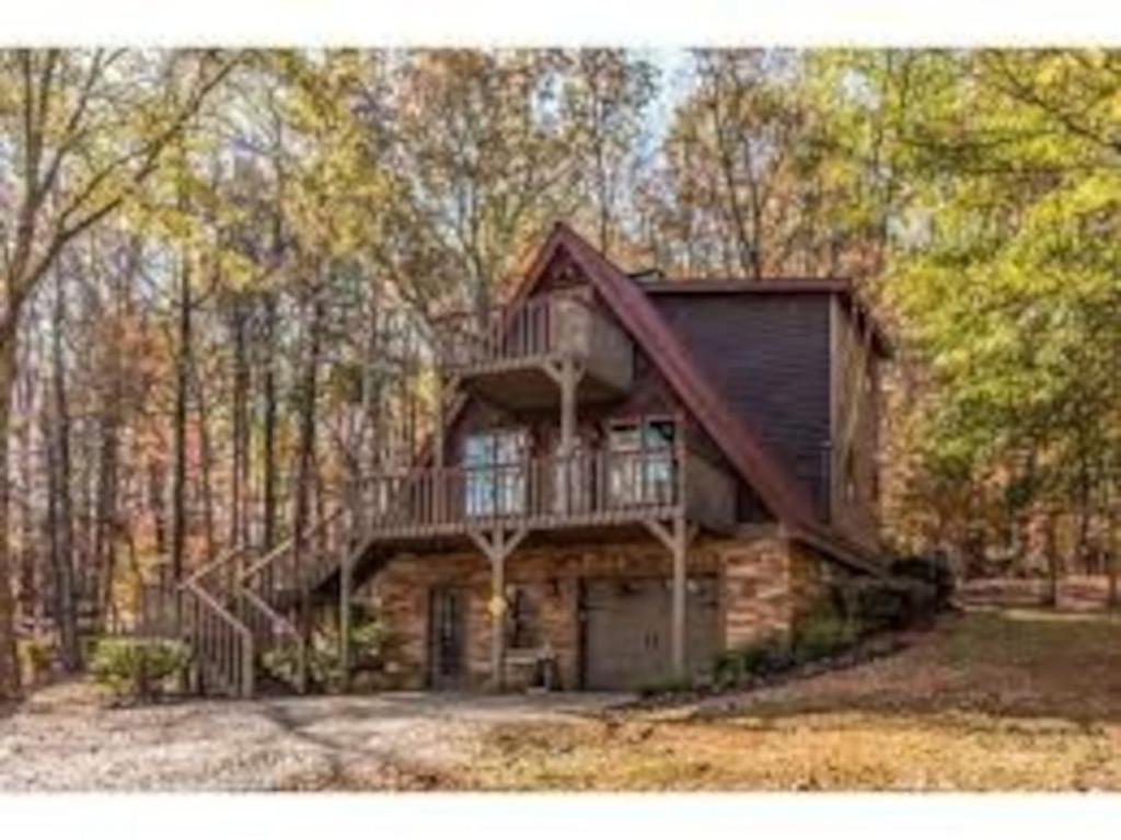 a log cabin in the woods with a balcony at Farmhouse in a Peaceful Paradise with Huge Hot tub in Gainesville
