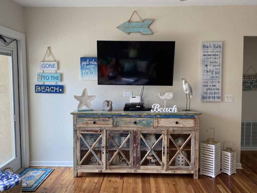 a living room with a tv on top of a wooden dresser at Seaside Serenity Direct Oceanfront in Ormond Beach